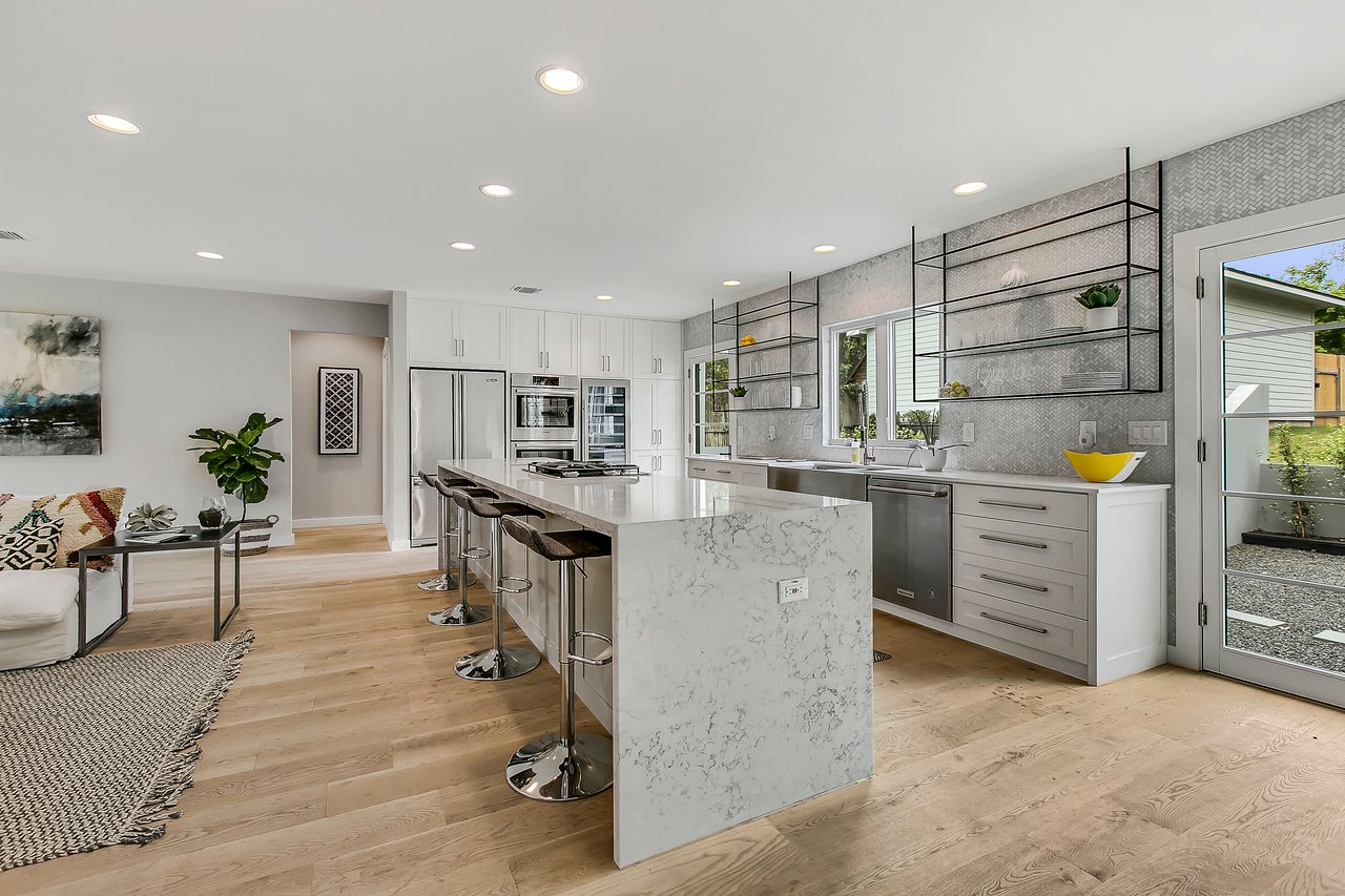 Kitchen at 1004 Maufrais Street in Clarksville (Old West Austin), Austin, TX, featuring a waterfall-edge island, stainless appliances, and a herringbone tile backsplash.