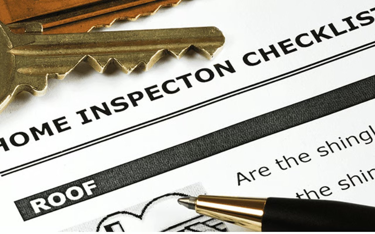 House keys and a pen on a home inspection checklist, open to the roof section.