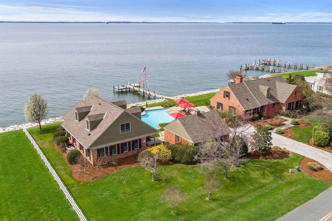 Waterfront homes with a swimming pool, private docks, and landscaped lawns beside the water.