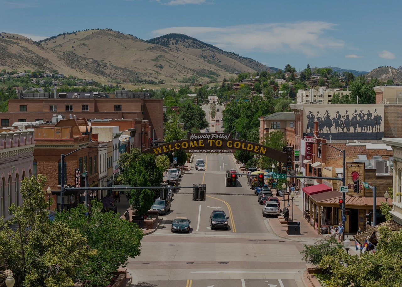 Downtown Golden street beneath the Welcome to Golden arch, with foothills rising behind the town.