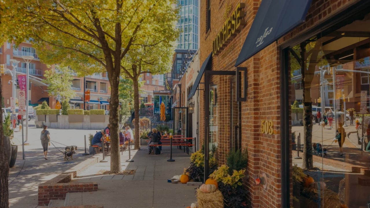 Autumn streetscape with outdoor café seating beside a brick storefront marked 903.