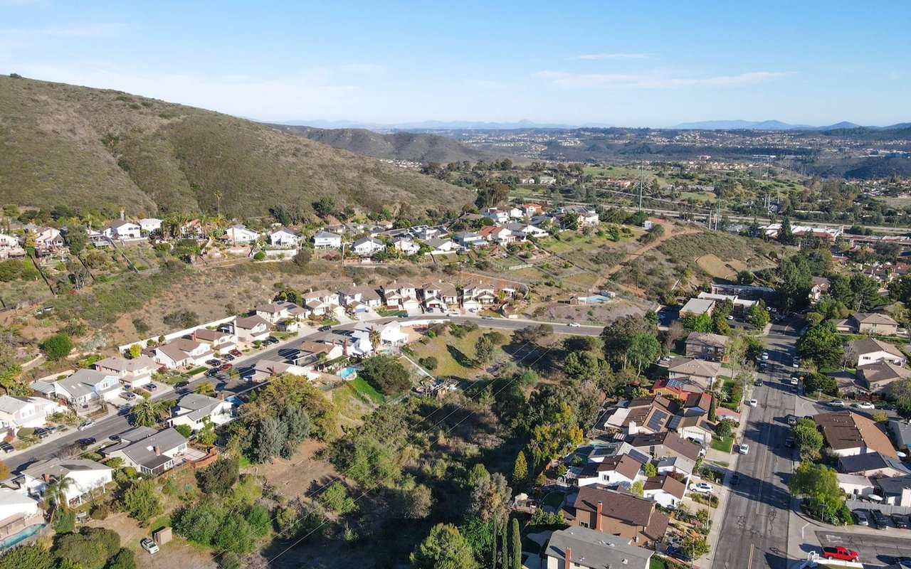 Aerial view of Carmel Valley homes beside scrub-covered hills and winding streets.