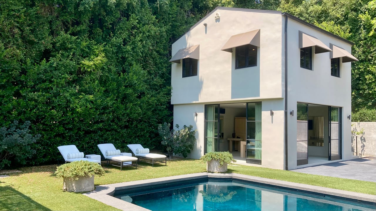 Modern two-story detached ADU in Los Angeles with stucco exterior, black-trim windows, backyard pool, and lounge seating.