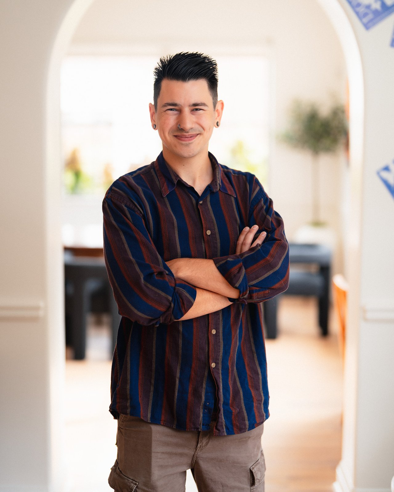 Skylar Brillante standing with arms crossed in a striped shirt.