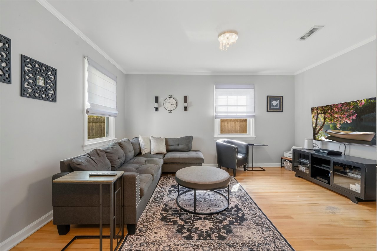 Living room with a gray sectional, patterned rug, round coffee table, and television.