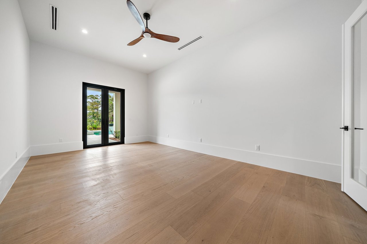Vacant room with light wood floors, a wood ceiling fan, and glass doors overlooking a pool.