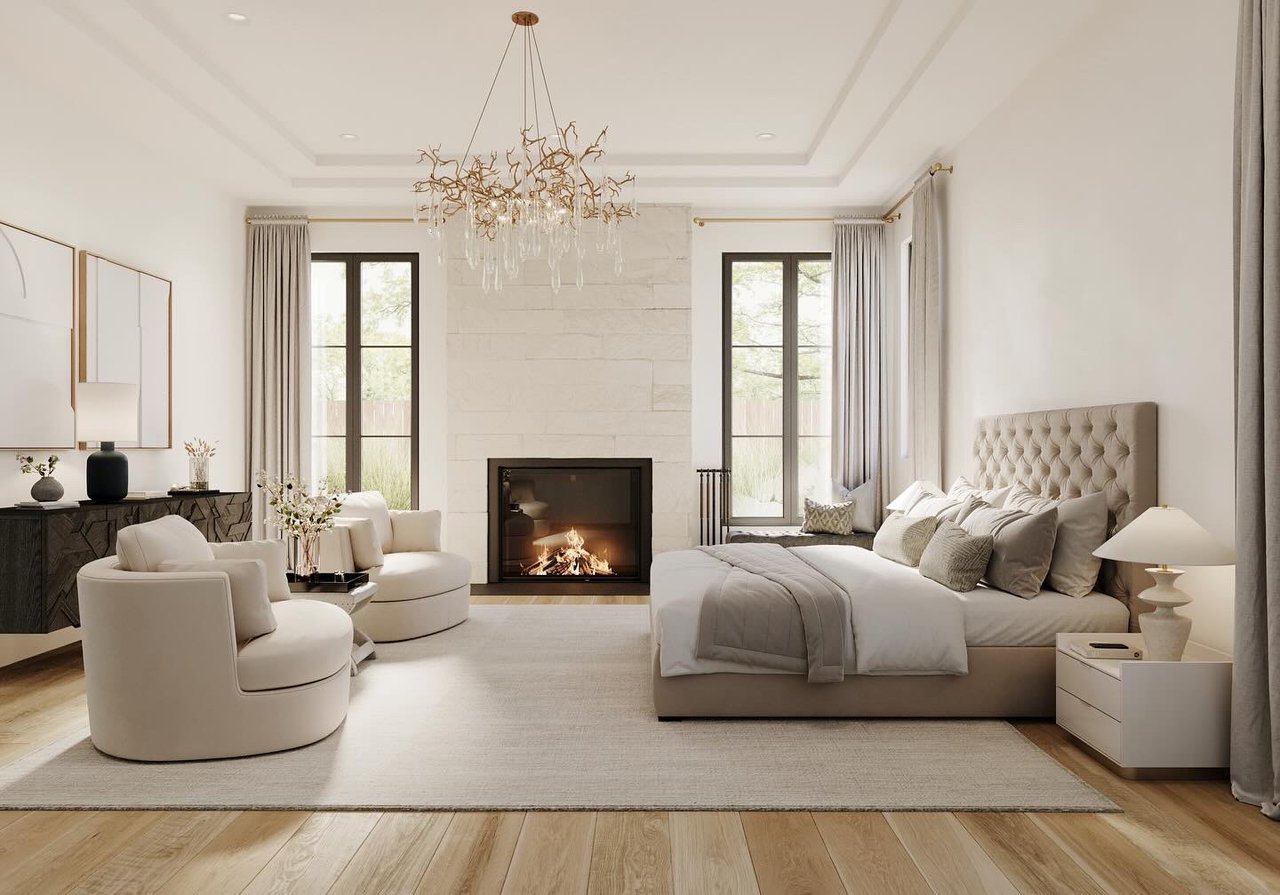 Modern bedroom featuring a cozy fireplace, neutral-toned bedding, elegant white stone walls, and contemporary round armchairs