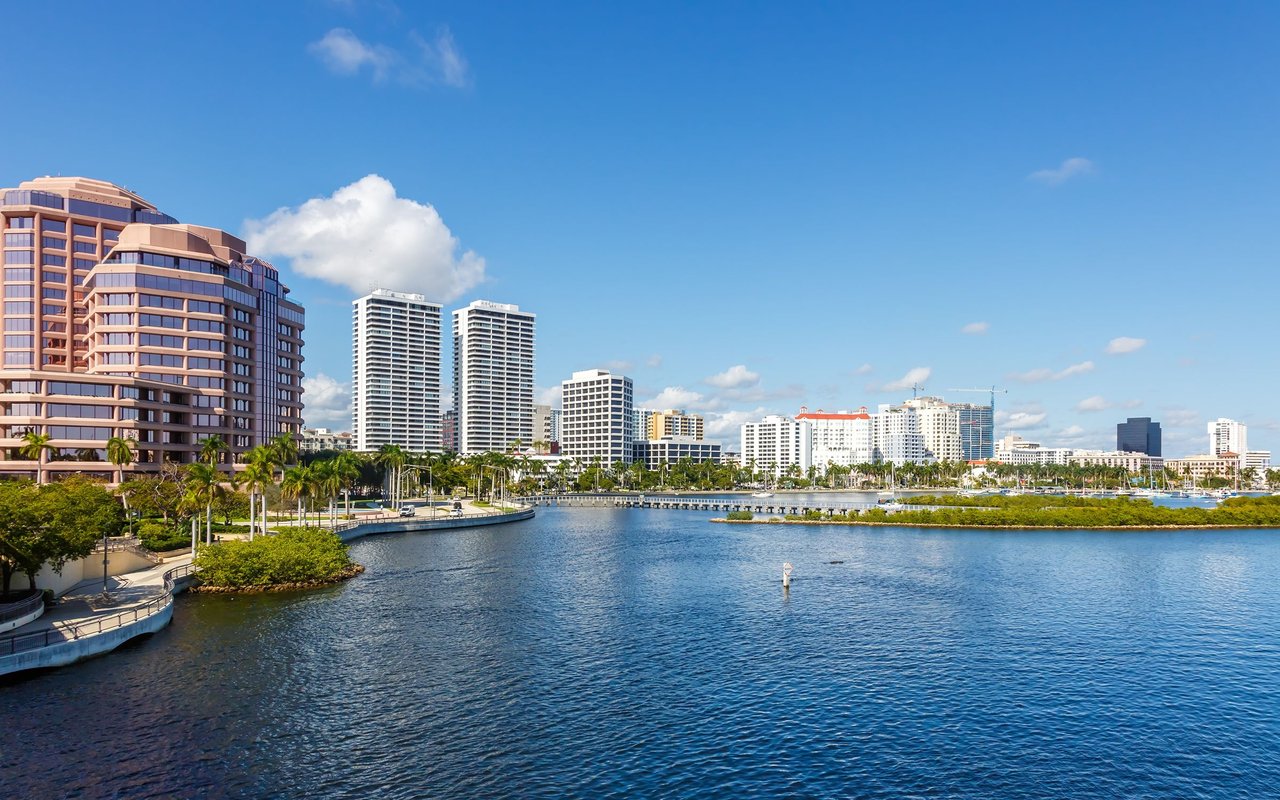 West Palm Beach waterfront skyline across the water, lined with high-rises and palm trees.