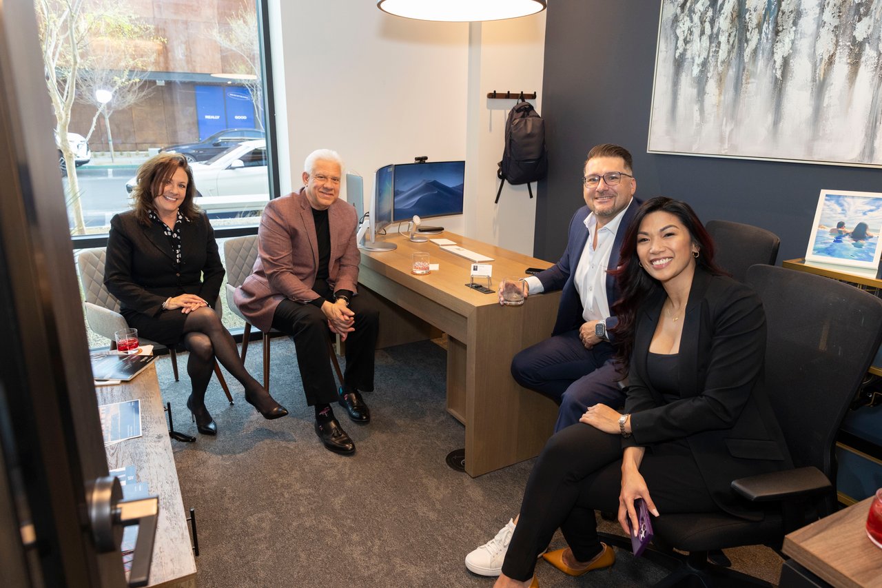 Four adults seated together in a real estate office.