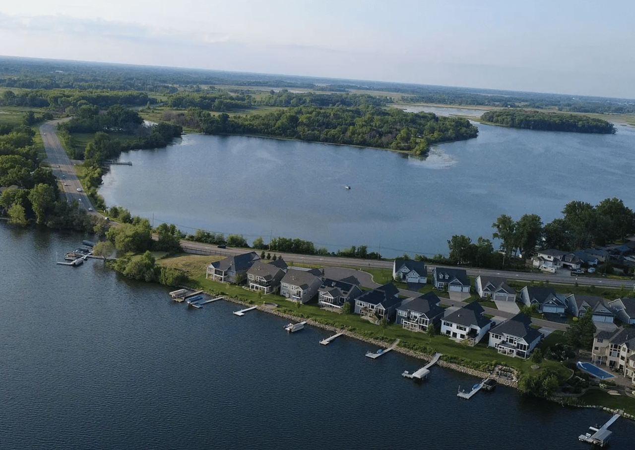Aerial view of lakeside homes with private docks along a broad, tree-lined lake.