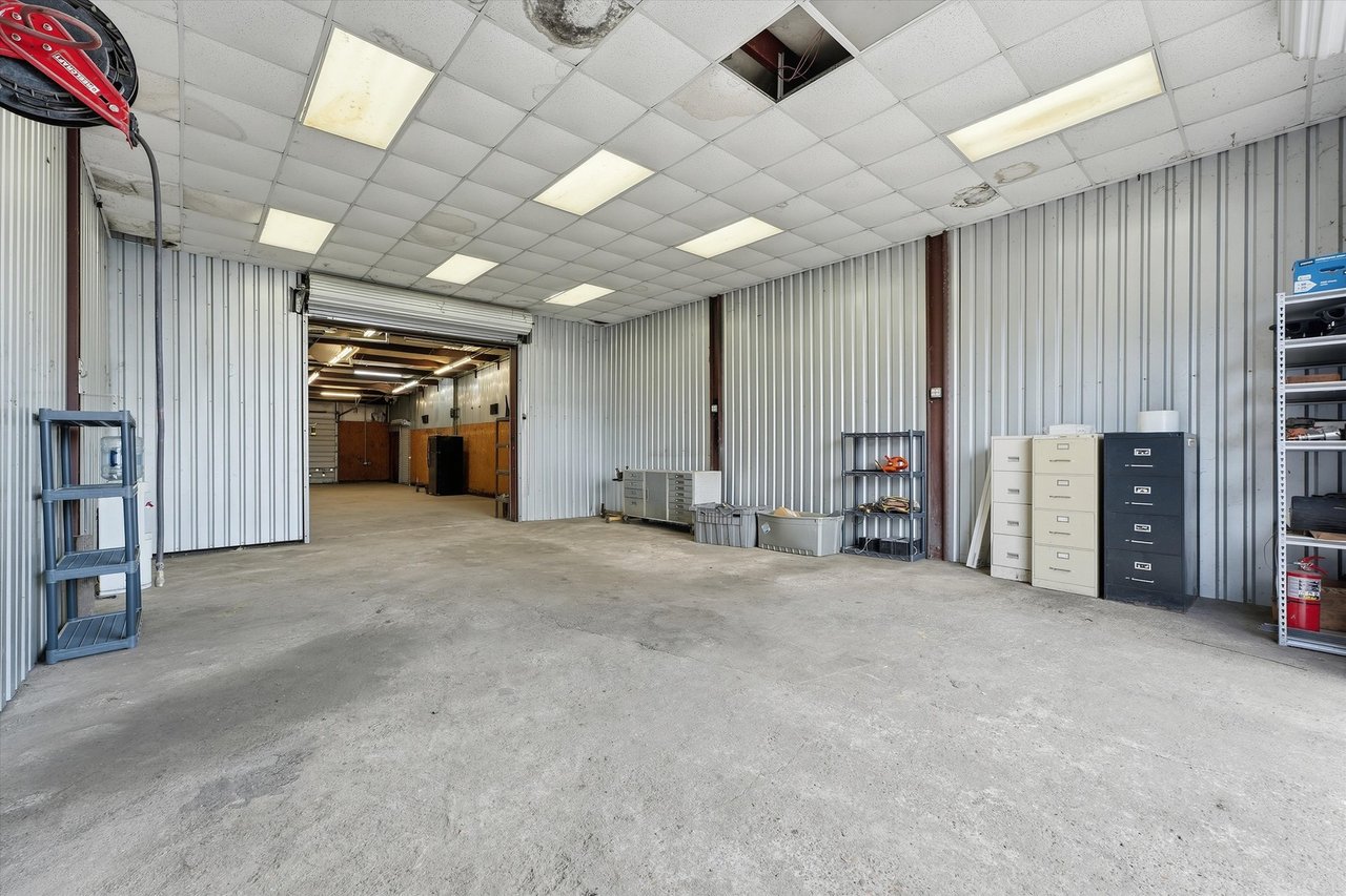 Workshop with corrugated metal walls, concrete floor, and an open roll-up doorway.