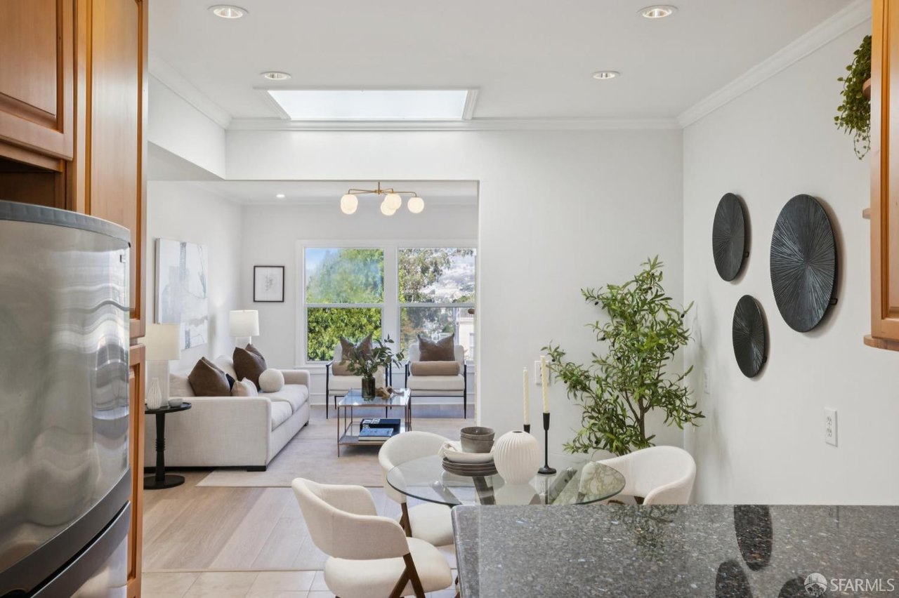 Open-plan kitchen and living room with wood cabinetry, granite island, and large windows.