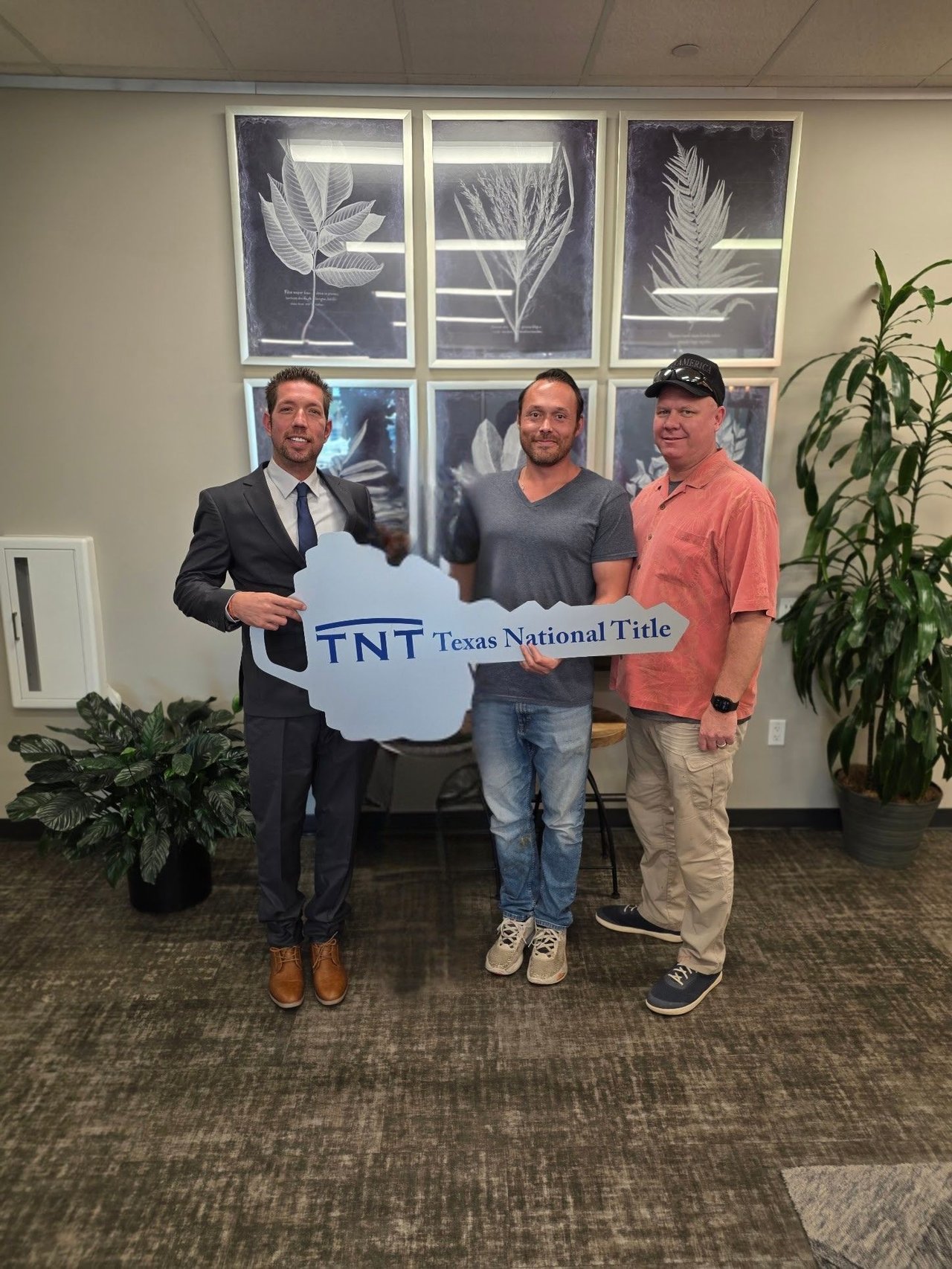 Three men hold a Texas National Title sign in an office.