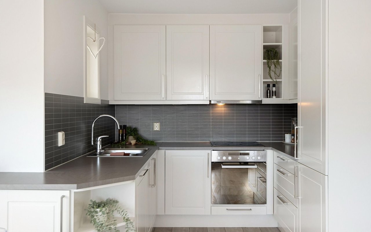 Bright kitchen with white cabinets, charcoal tile backsplash, and stainless-steel appliances.
