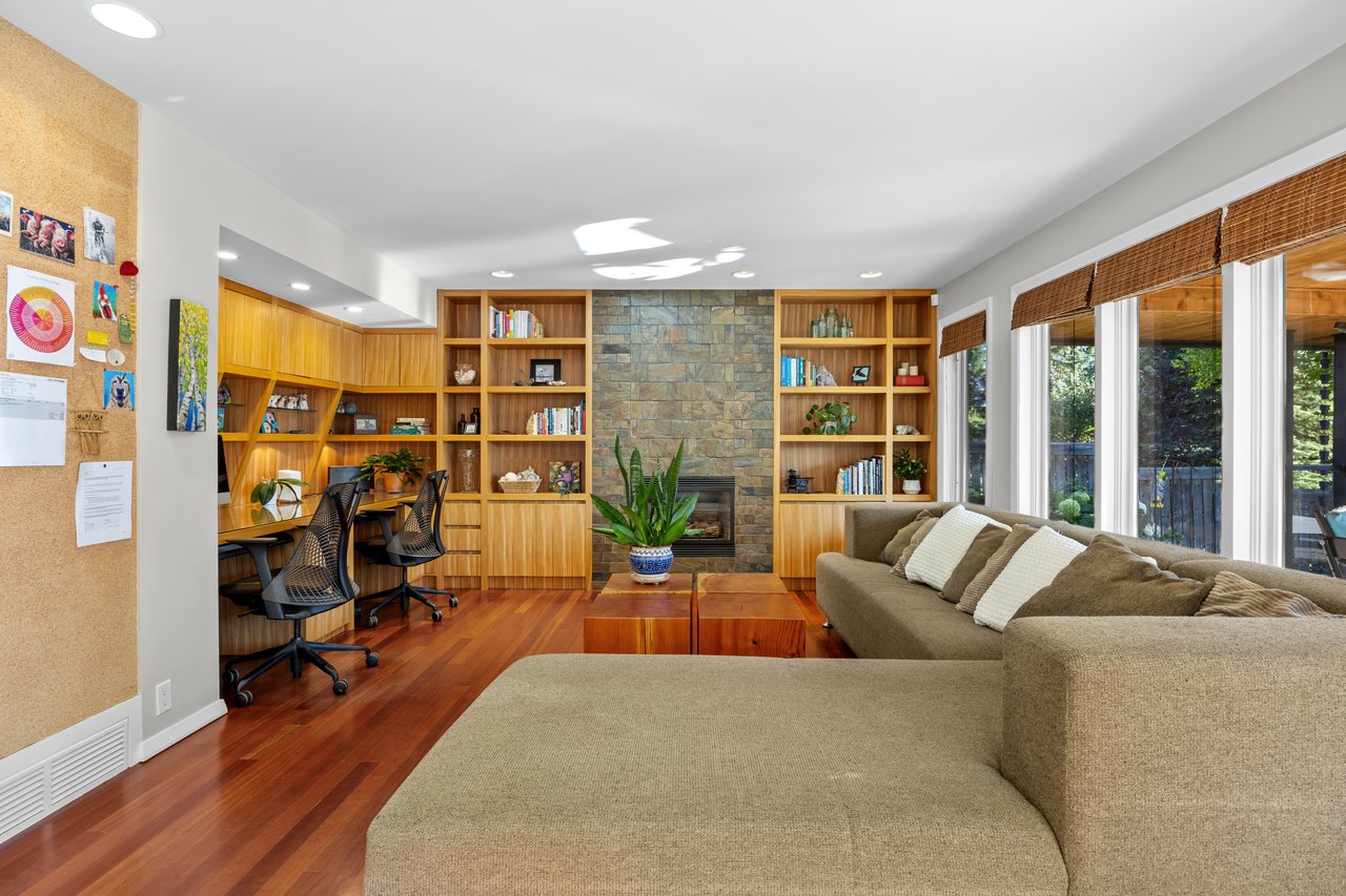 Living room with a sectional sofa, built-in bookshelves and desk nook, and stone fireplace.
