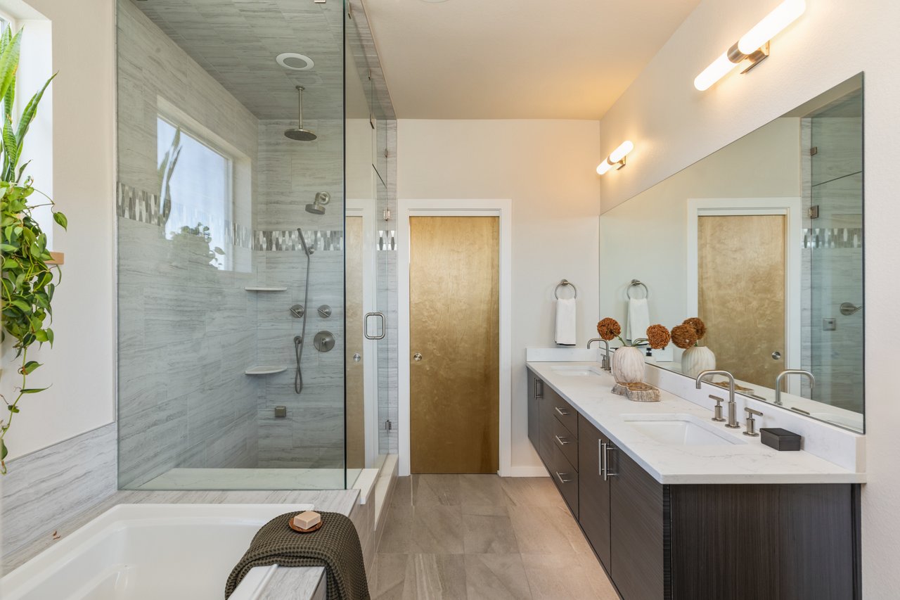 Primary bathroom with a glass-enclosed shower, soaking tub, and long dark-wood vanity