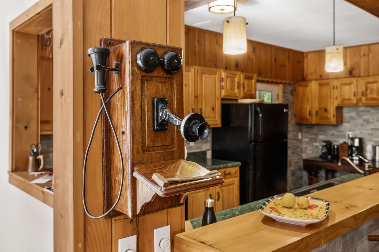 Wood-paneled kitchen with an antique wall-mounted telephone beside the island.