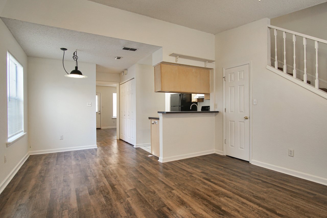 A spacious, uncluttered living room featuring polished hardwood floors and ample natural light.