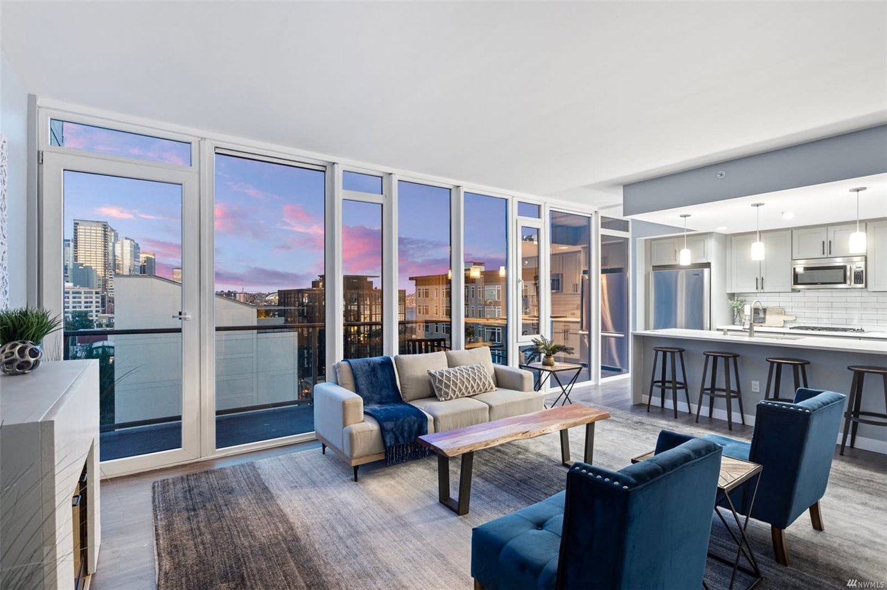 Contemporary condo living area with floor-to-ceiling windows capturing the city skyline at dusk, exuding upscale comfort.