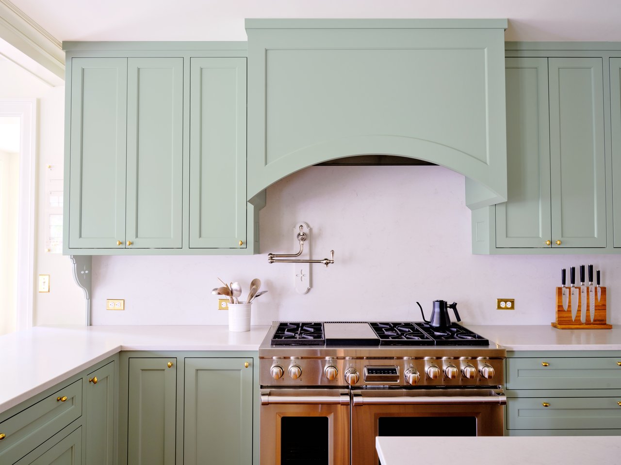 Kitchen with sage-green cabinets, a stainless-steel range, and a wall-mounted pot filler.