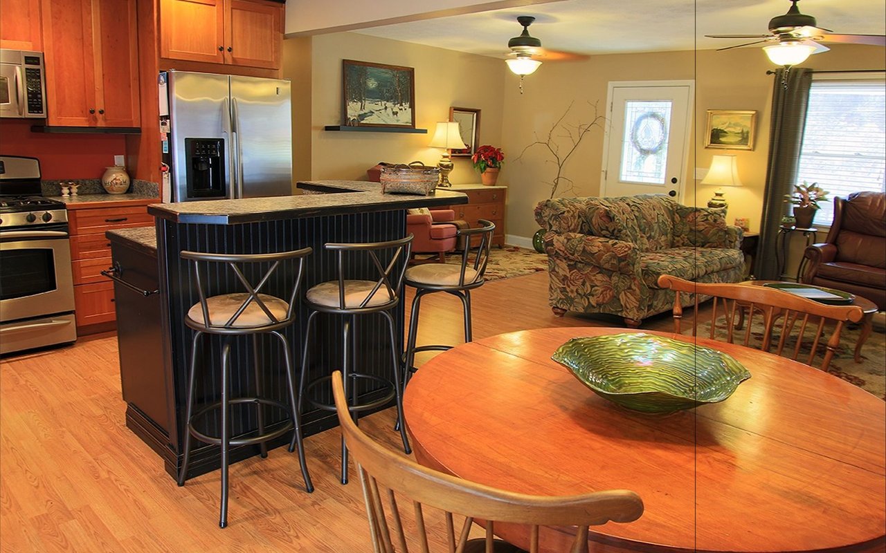 Open-plan kitchen and dining area with a dark breakfast bar and round wooden table.