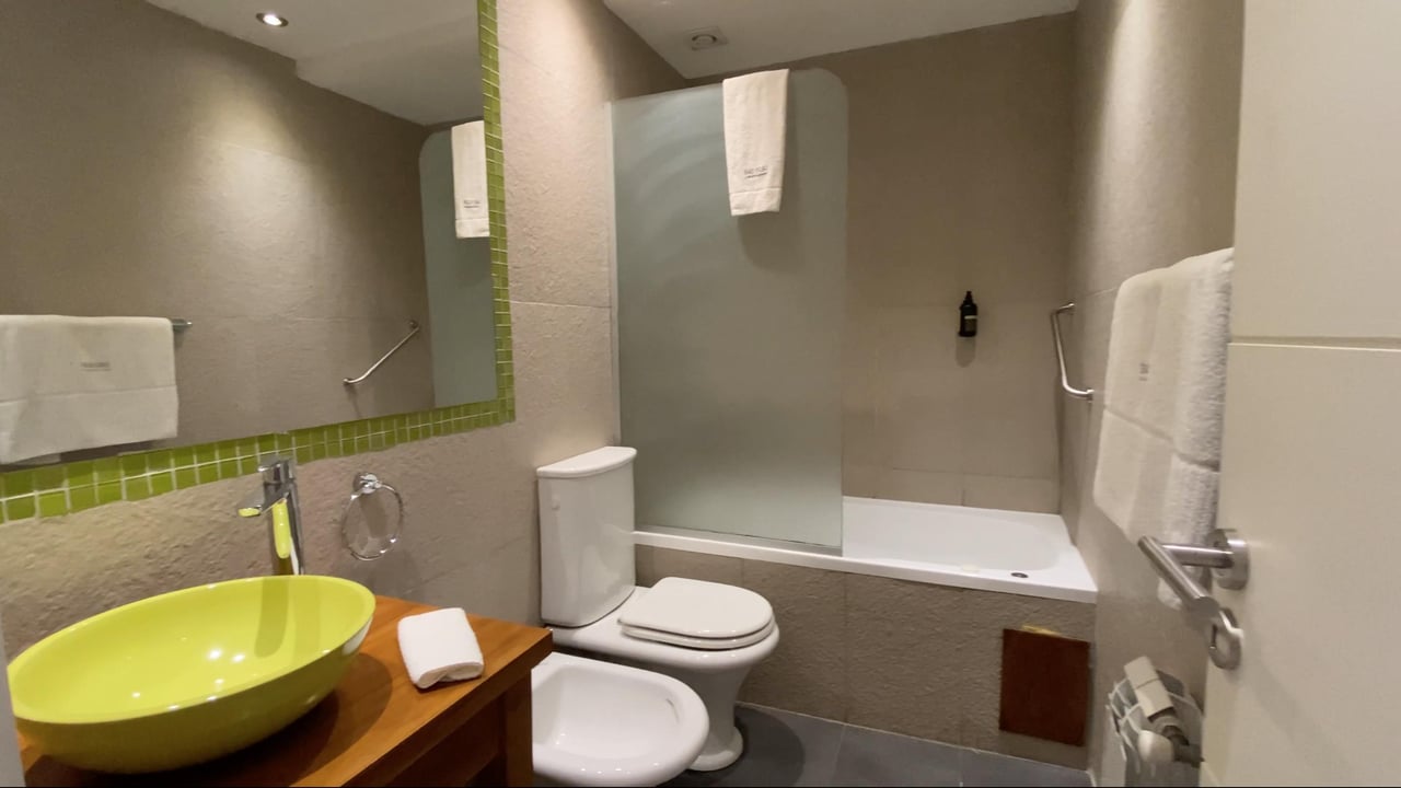 Bathroom with a lime-green vessel sink and bathtub behind a glass shower partition