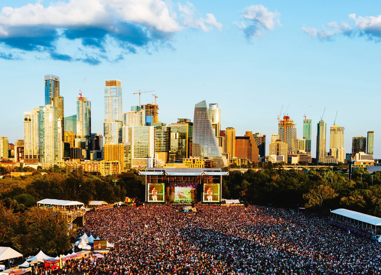 A huge music festival crowd faces a stage, with downtown Austin’s skyline behind it.