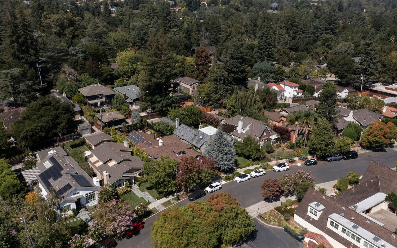 Aerial view of Los Altos homes among mature trees, with solar panels on several roofs.
