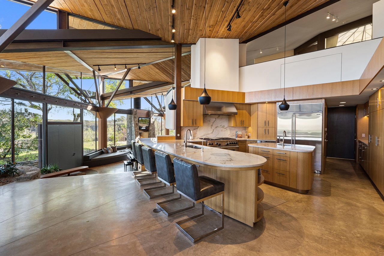 Chef's kitchen with a Calacatta Macaubas quartzite island, rift-sawn white oak cabinetry and pendant lighting, Lick Creek Lodge, Spicewood, Texas.
