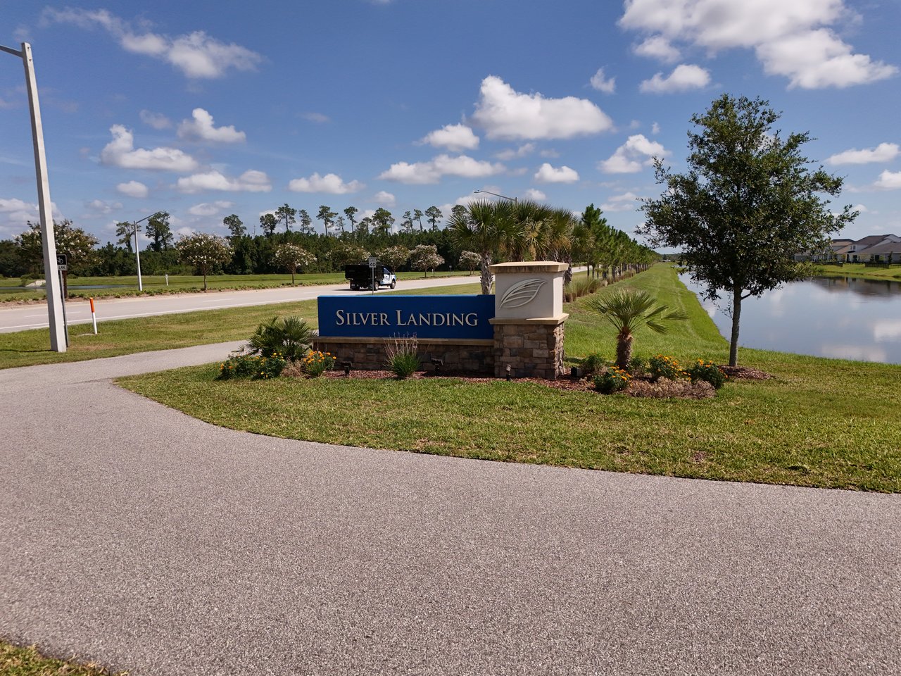 Silver Landing community entrance sign beside a road, with a landscaped pond and homes behind it.