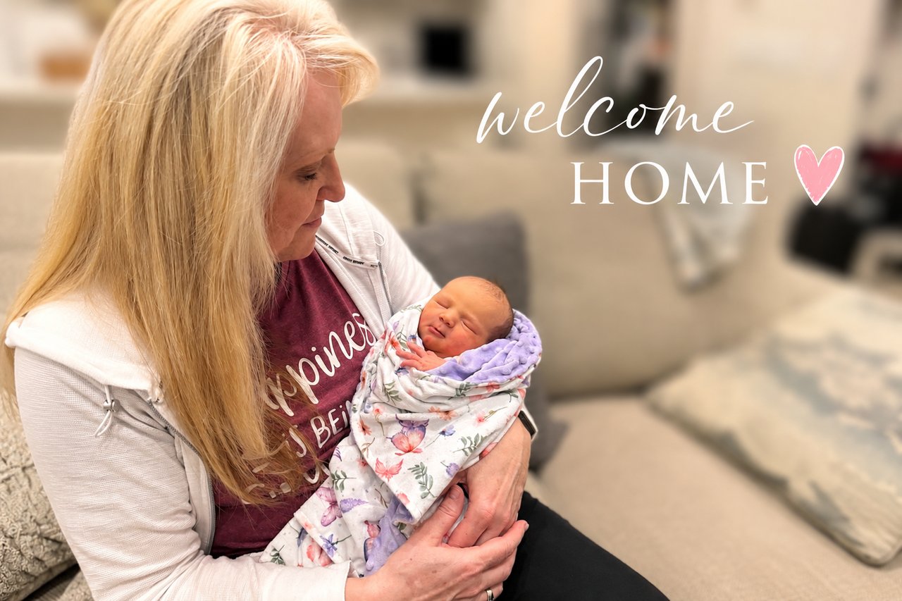Sharla Ellis holding her newborn granddaughter with “Welcome Home” text, reflecting on family, motherhood, and the meaning of home.