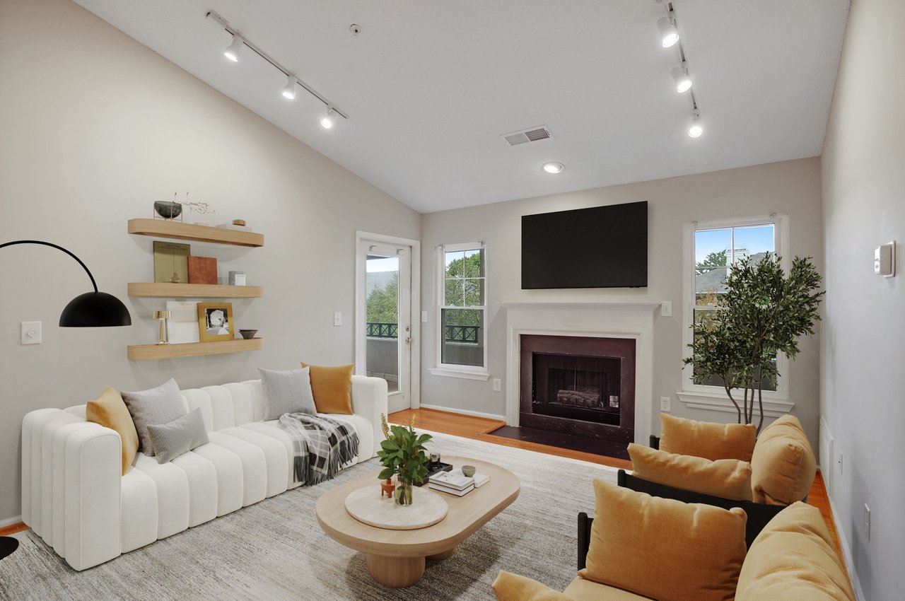 Living room with a fireplace, wall-mounted TV, white sofa, and mustard accent chairs.