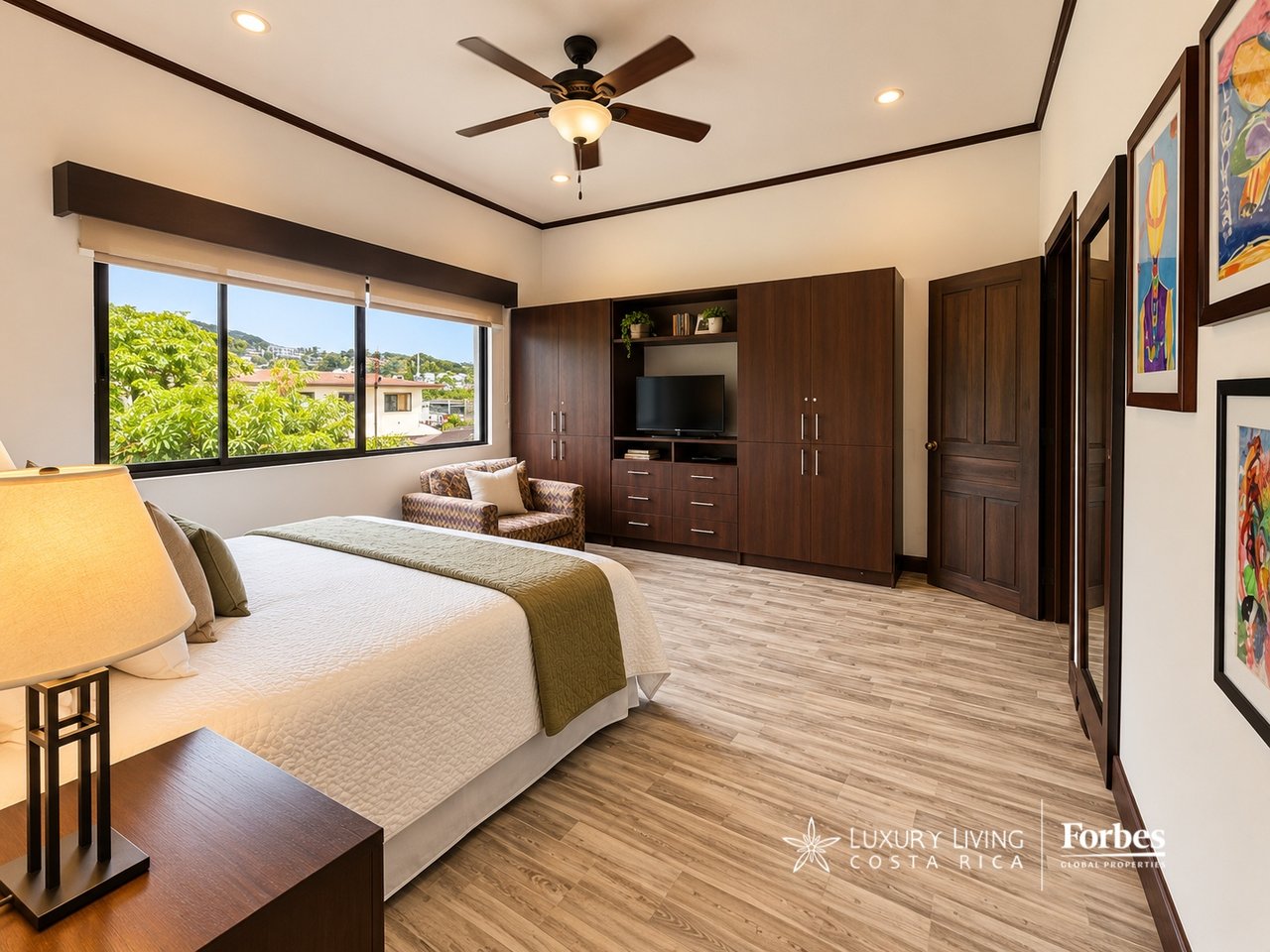 Furnished bedroom with dark wood cabinetry, a large window, and a bed with a green throw.