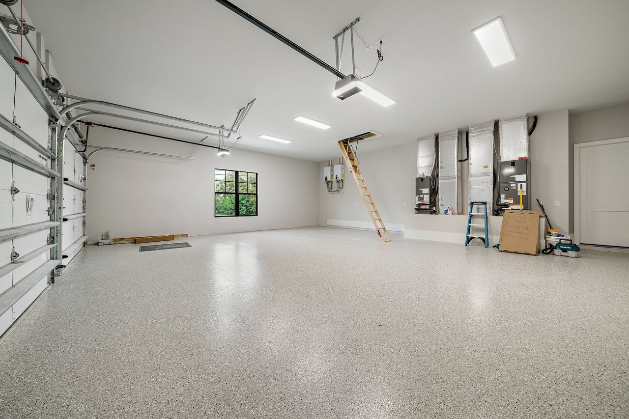Spacious new-construction garage with speckled flooring and exposed HVAC equipment.