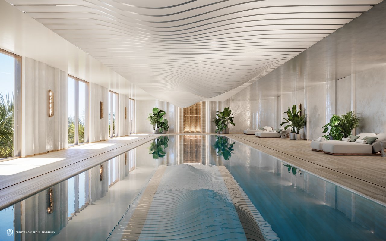 Indoor pool with a sculptural wave ceiling, floor-to-ceiling windows, and white lounge seating.