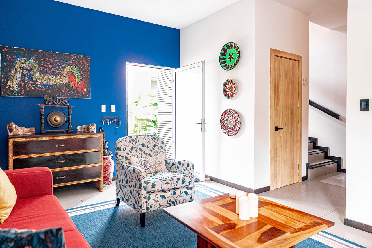 Living room with a blue accent wall, patterned armchair, red sofa, and wooden coffee table.