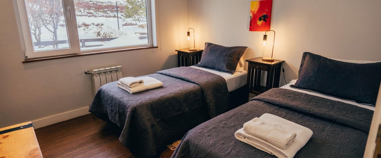 Bedroom with two single beds and snowy scenery visible through the window.