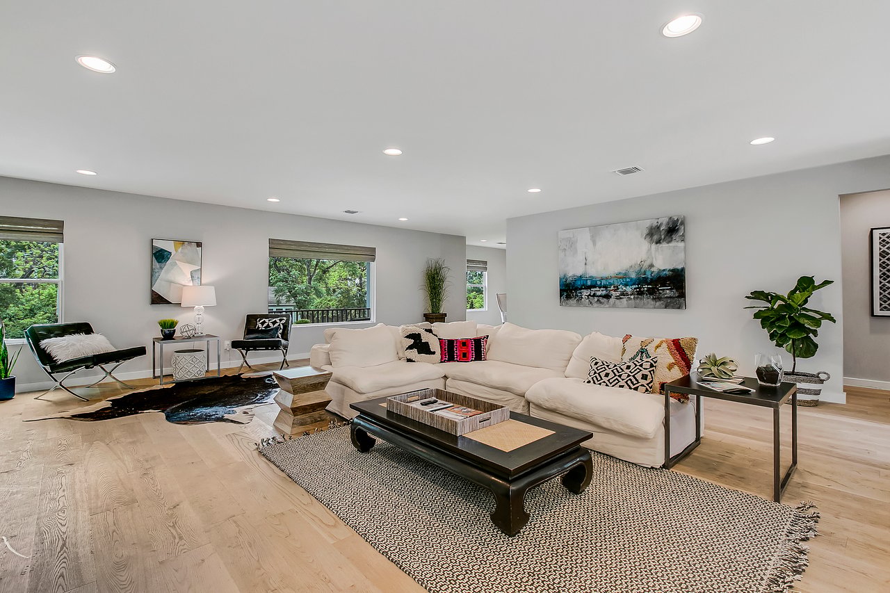 Living room at 1004 Maufrais Street in Clarksville (Old West Austin), Austin, TX, with a white sectional sofa, cowhide rug, and wide-plank white oak floors.