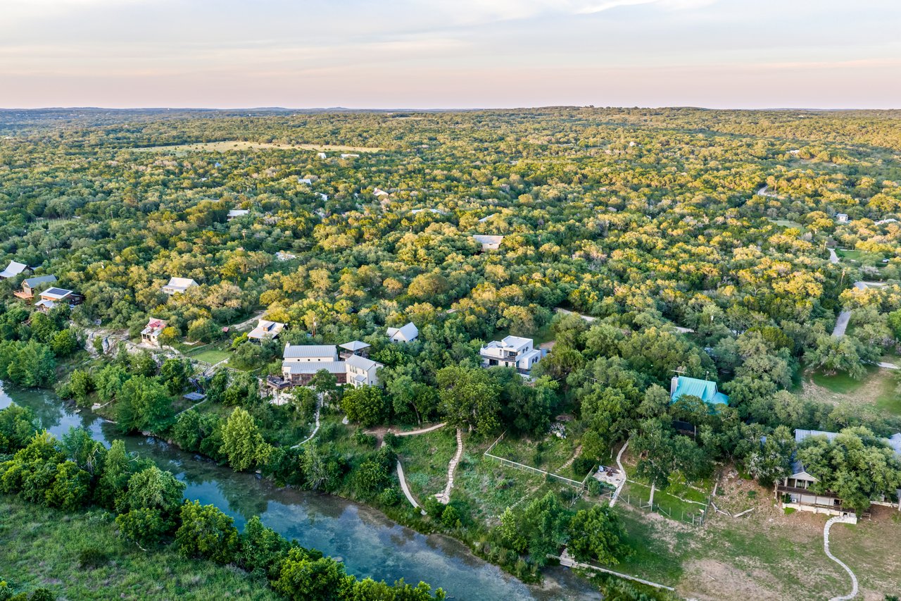 Aerial view of a wooded riverside property with scattered homes and a winding river.