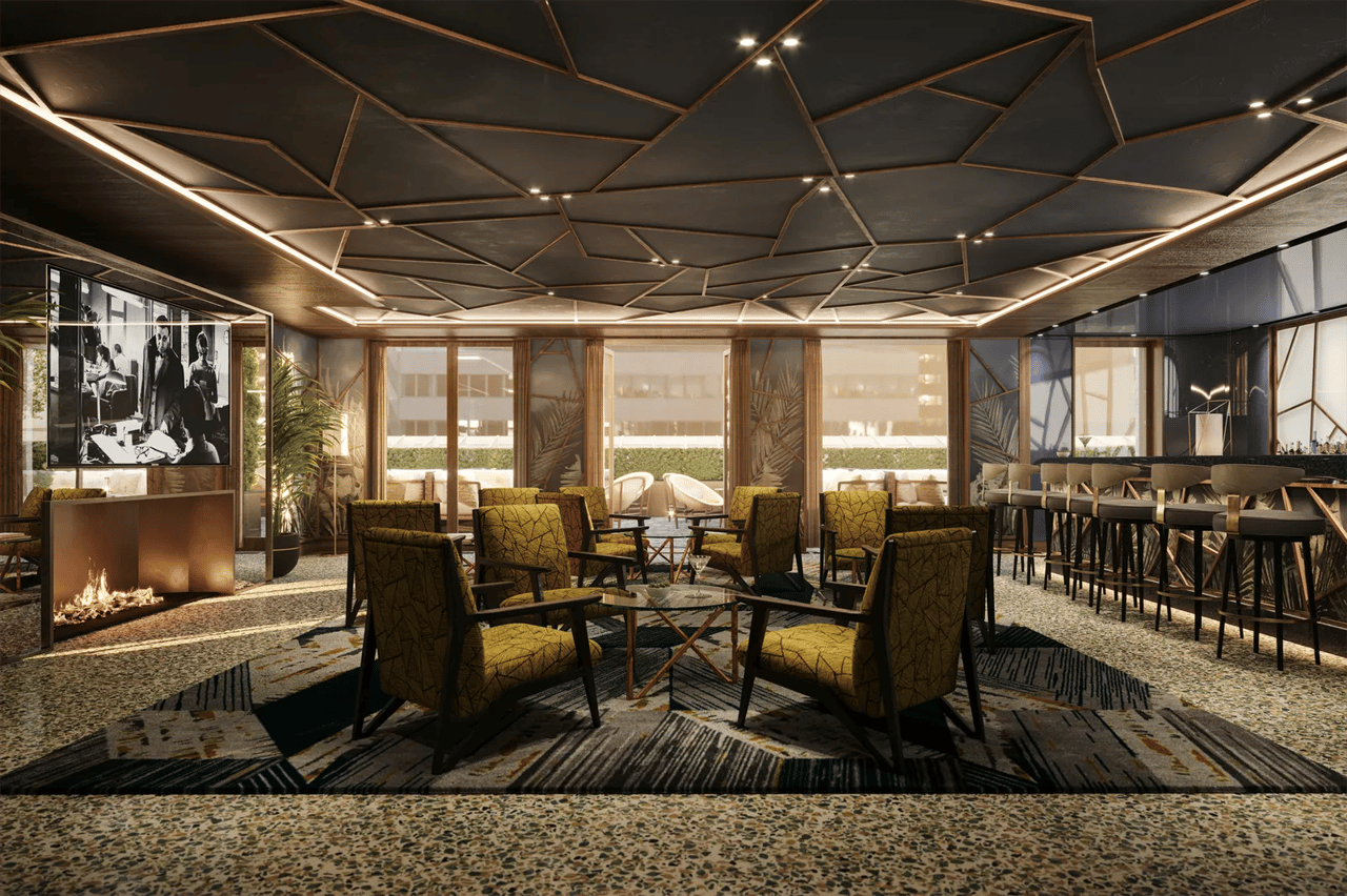 Amenity lounge with patterned armchairs, a fireplace, and a bar beneath a geometric ceiling.