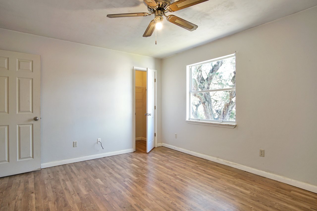 Empty room featuring hardwood floors and a ceiling fan, creating a spacious and airy atmosphere.