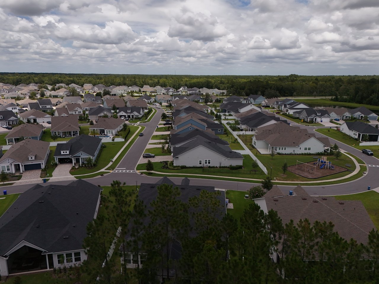 Aerial view of a neighborhood with detached homes, curving streets, and a small playground.