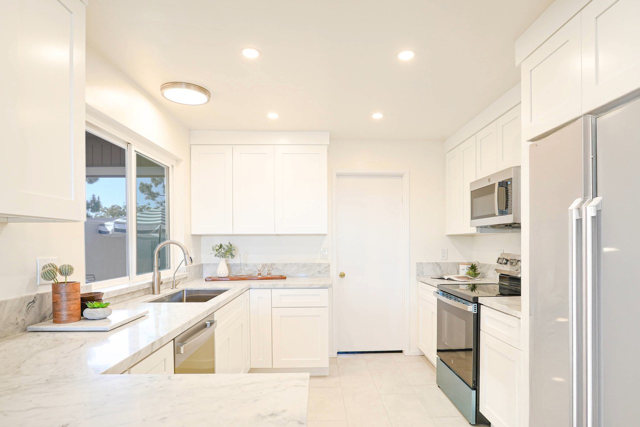 Spacious modern kitchen at 6321 Caminito Luisito in San Diego, CA 92111, featuring white shaker cabinets, stainless steel appliances, quartz countertops, large window with natural light, and sleek contemporary design.