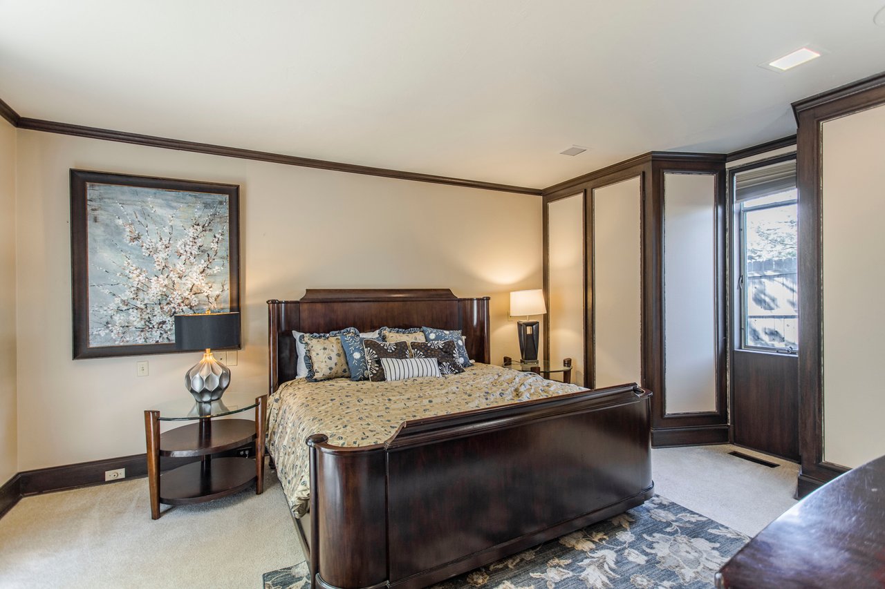 Bedroom with a dark wood bed, matching cabinetry, and floral artwork.