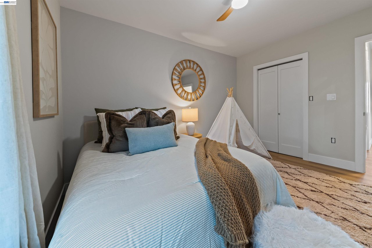 Staged bedroom with pale blue striped bedding, a knitted throw, and a small white teepee.