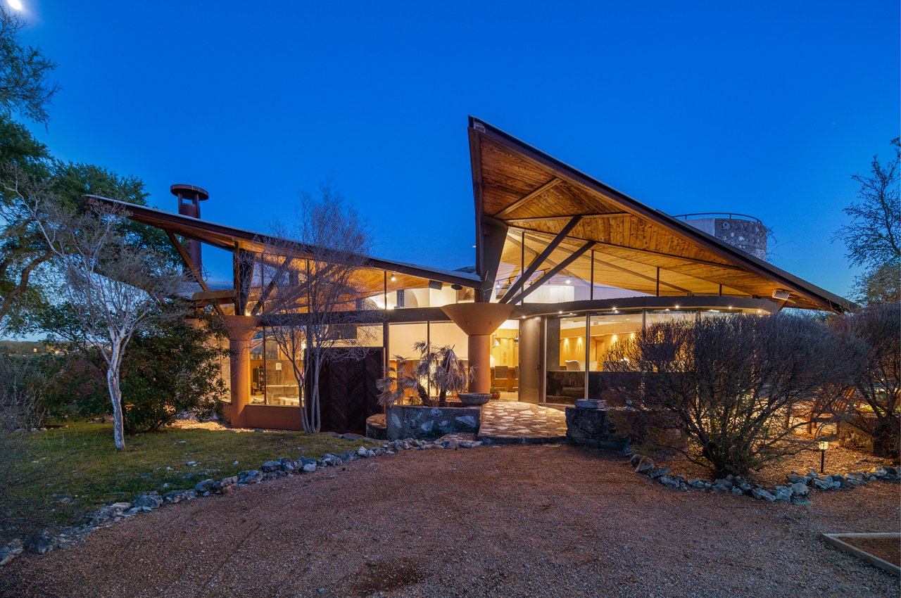 Twilight rear elevation showing the winged roofline and lit glass walls, architect John Covert Watson, builder Don Crowell, project manager Peter Dick.