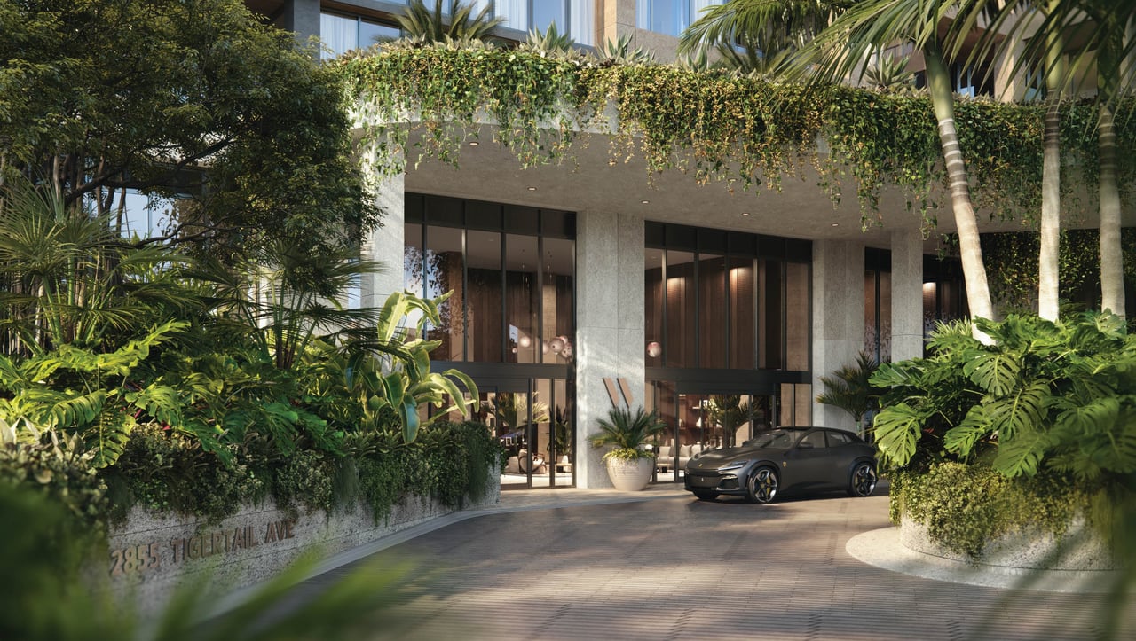 The Well’s modern entrance framed by tropical landscaping, with a dark car in the driveway.