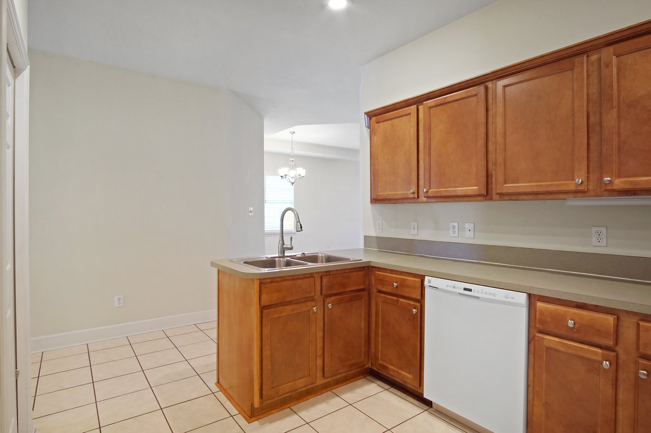 Kitchen at 5441 Hampton Hill Circle, Tallahassee, Florida 32311 with wood cabinets, double sink island, dishwasher, and tile flooring.
