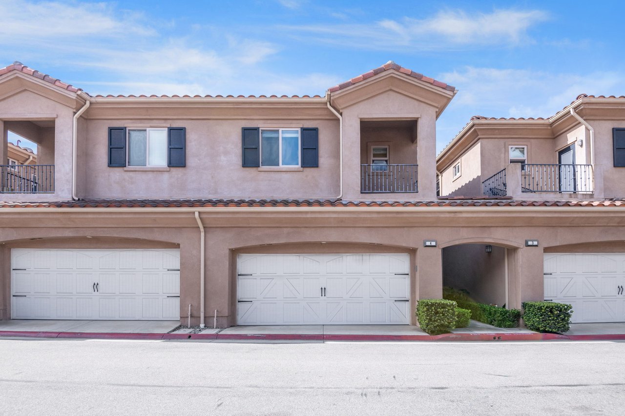 Front exterior of Mediterranean-style townhouse at 20402 Santa Ana Ave #4 in Newport Beach with attached two-car garage