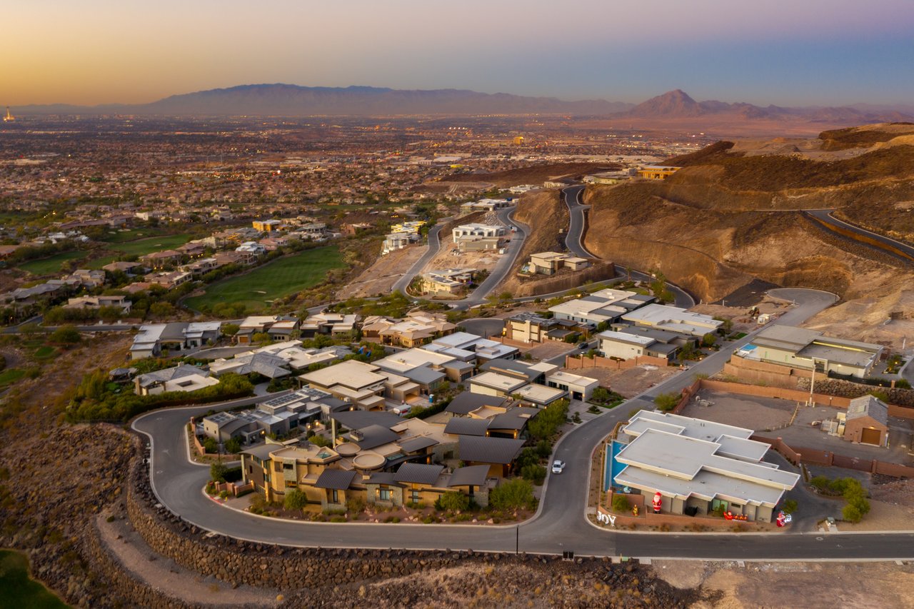 Hillside homes and winding roads overlook the Las Vegas Valley at sunset.